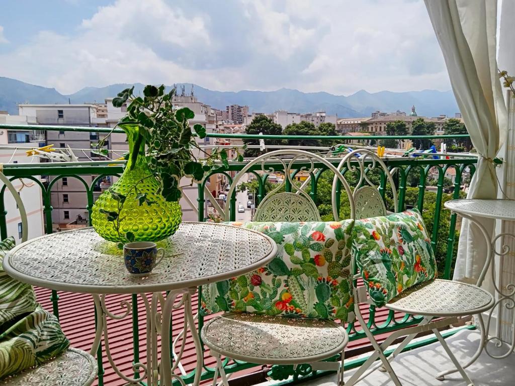 a table and chairs with a vase on a balcony at Casa Amari alla Zisa HOSTEL in Palermo