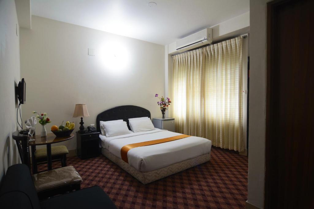 1 dormitorio con cama, escritorio y ventana en Holiday Xpress en Dhaka