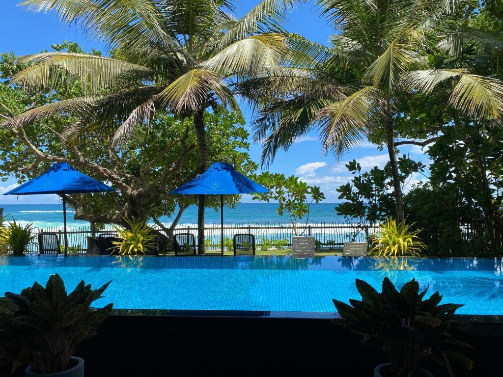 una piscina con palme e l'oceano di Royal Indigo Villa a Talpe