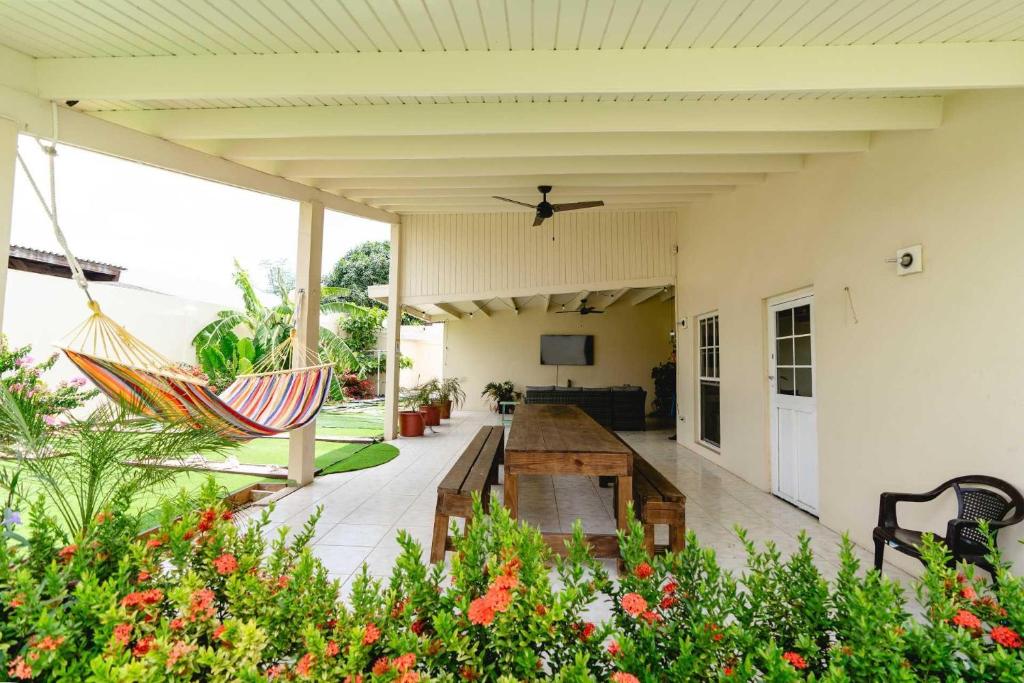 a patio with a hammock and a table and chairs at PCH23N- Close to Mangel Halto - Breezy Getaway 3BR in Savaneta