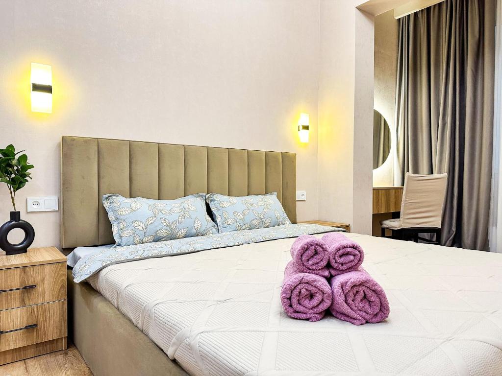 um quarto com uma cama com toalhas roxas em Luxury two-room apartment with beautiful mountain views em Almaty