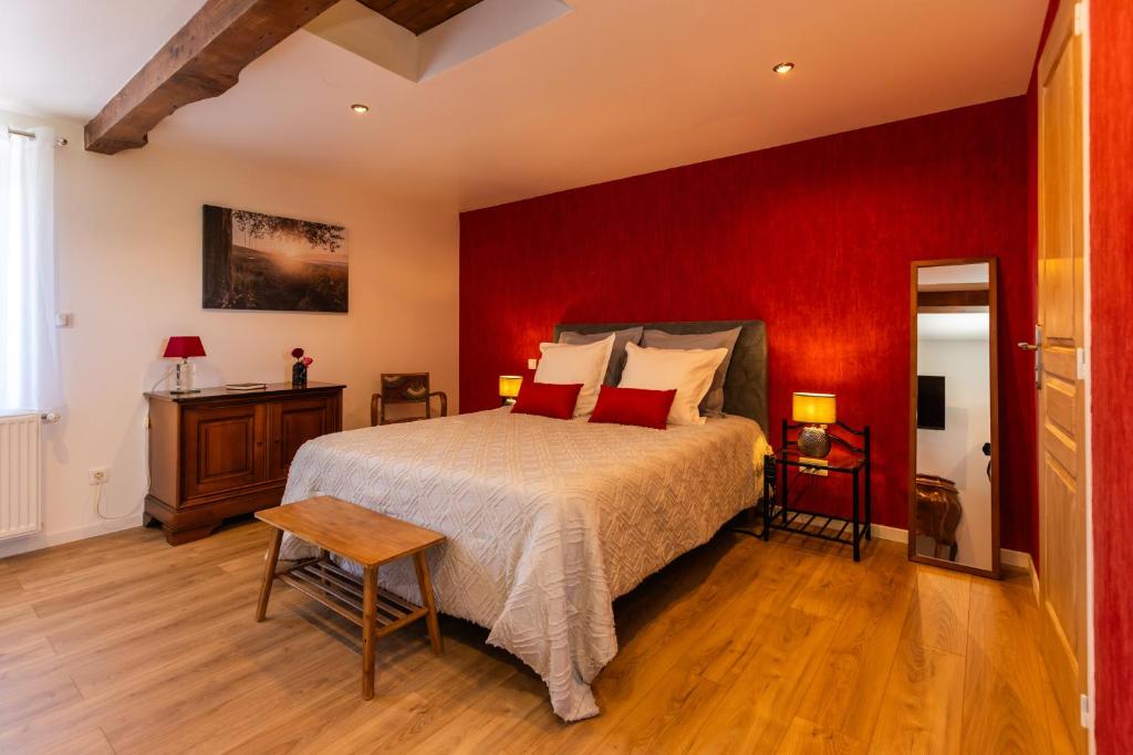 - une chambre avec un grand lit et un mur rouge dans l'établissement La Longère Forézienne, à Sainte-Agathe-la-Bouteresse