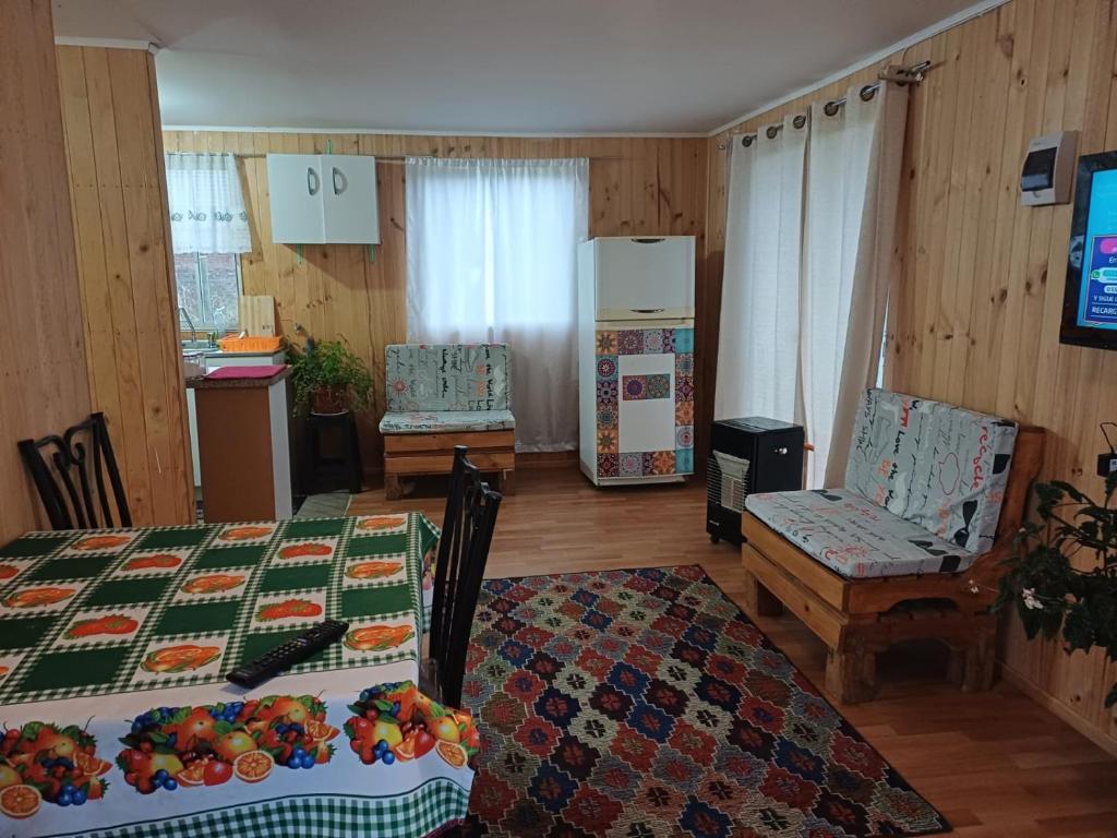 een woonkamer met een tafel en stoelen en een keuken bij Cabañas Lomas de Putagan in Linares
