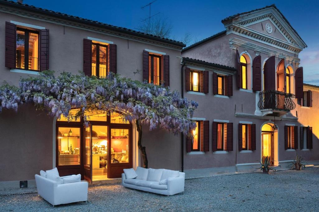 un edificio con dos sillas blancas delante de él en La tua villa, en Motta di Livenza