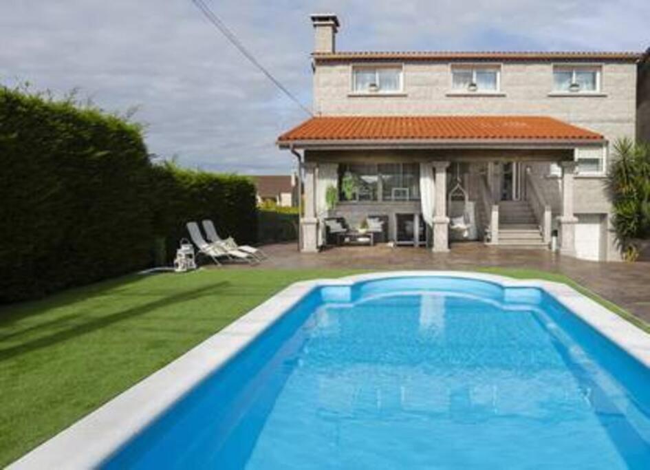 a large blue swimming pool in front of a house at Apartamento con Piscina Ribadumia in Ribadumia