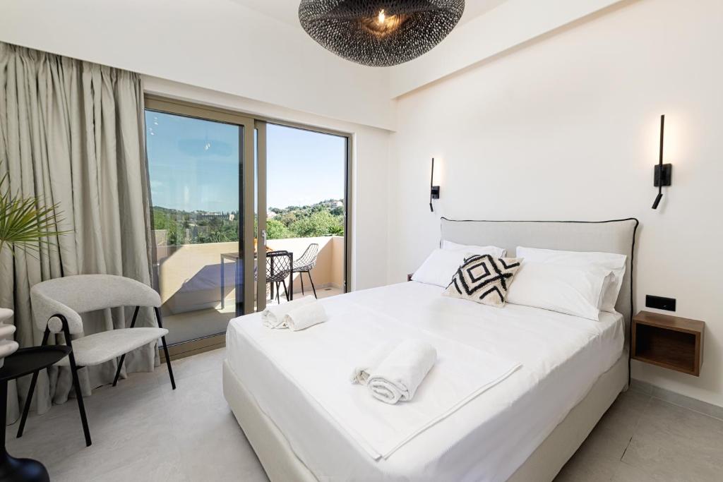 a white bedroom with a large bed and a balcony at Little Corfu in Dassia