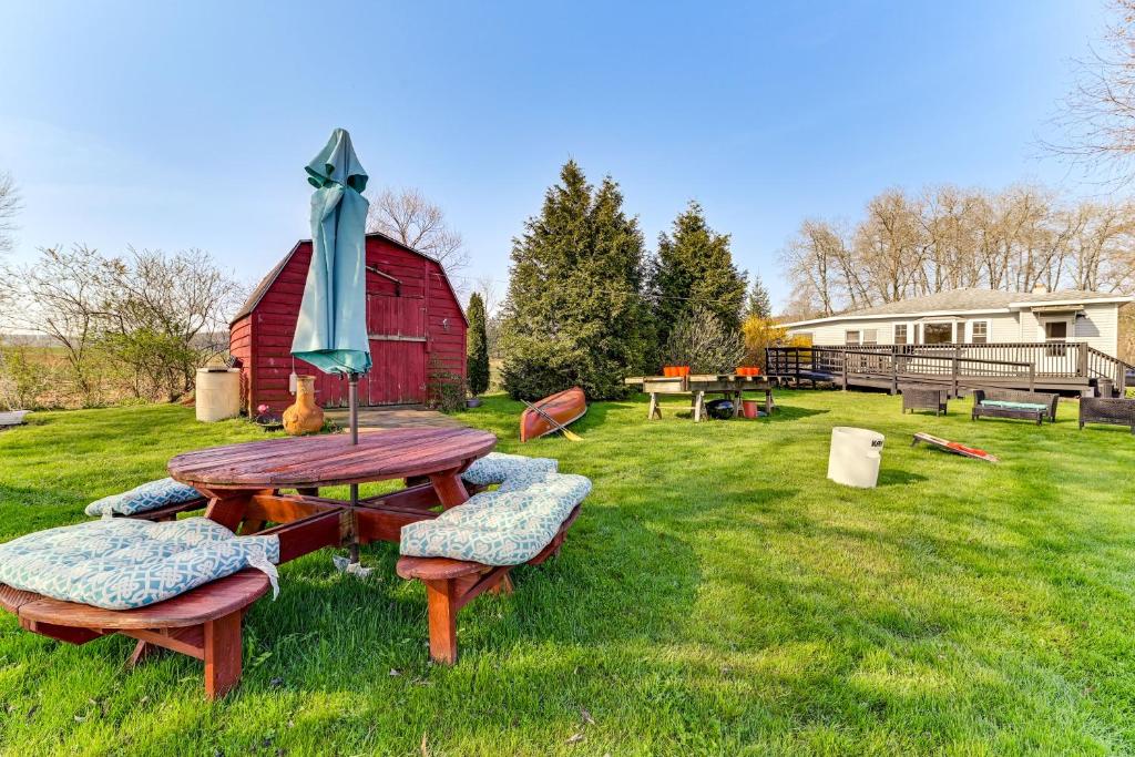 une table de pique-nique et des bancs dans une cour avec une grange rouge dans l'établissement Loon Lake Home with Private Boardwalk and Dock, 