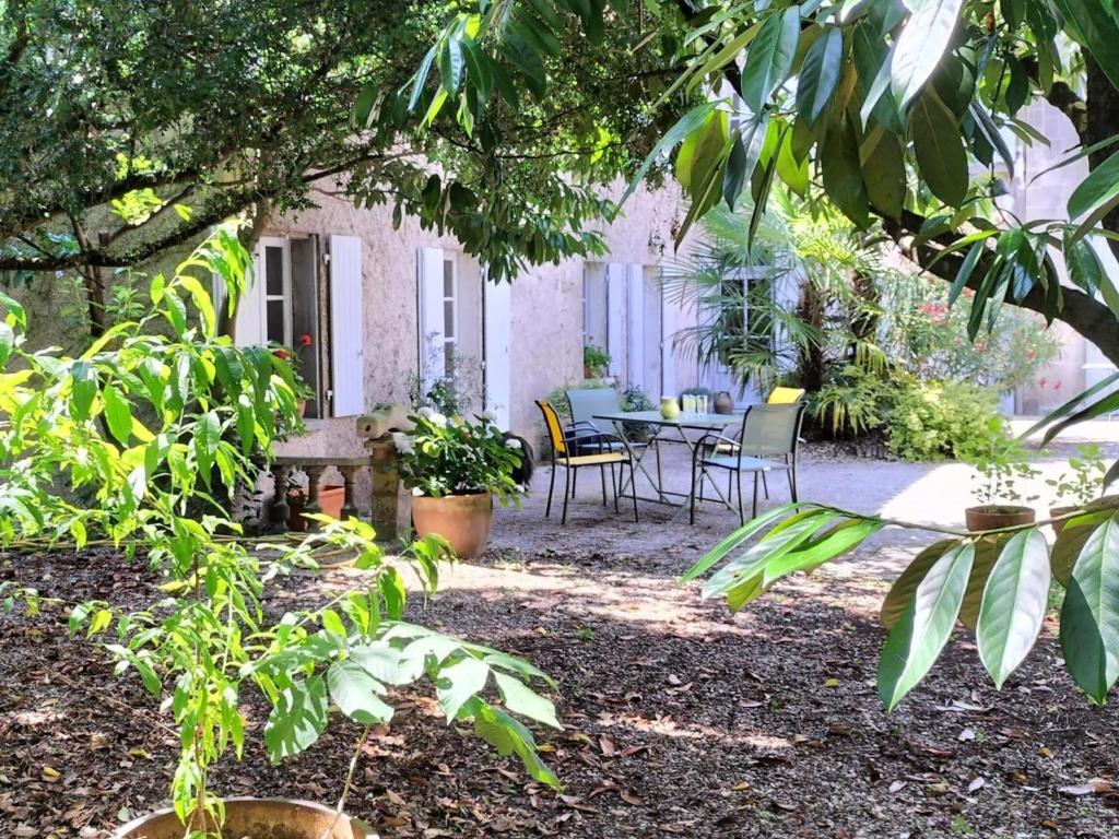 une maison avec une table et des chaises dans une cour dans l'établissement Gîte cosy avec jardin clos, terrasse et piscine à proximité, idéal pour famille et détente - FR-1-653-254, à Châteauneuf-sur-Charente