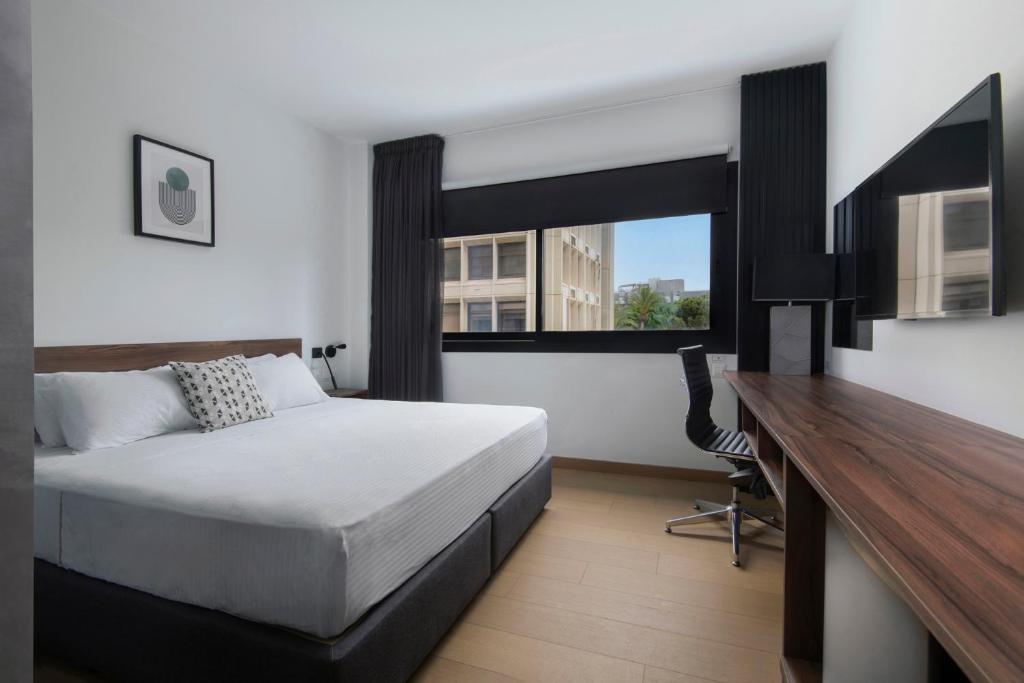 尼科西亞的住宿－Urban Habitat Executive Suites，一间卧室配有一张床、一张书桌和一个窗户。
