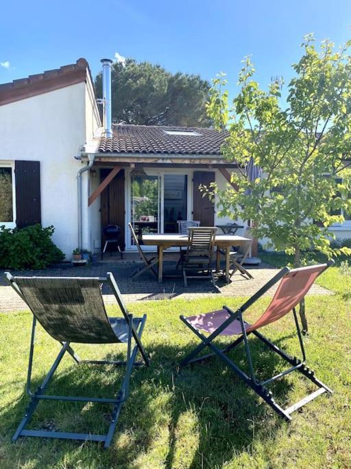 deux chaises assises dans l'herbe devant une maison dans l'établissement Maison (4pers) confortable entre bassin et océan, à Arès