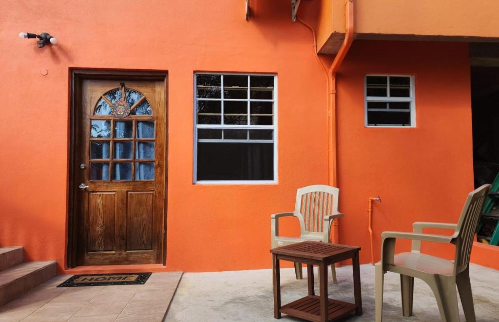 pomarańczowy dom z dwoma krzesłami i drzwiami w obiekcie ZionGates w mieście Castries