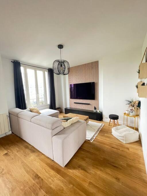 - un salon avec un canapé blanc et du parquet dans l'établissement Appartement chaleureux et lumineux en plein centre, à 10 min du RER, à Saint-Gratien