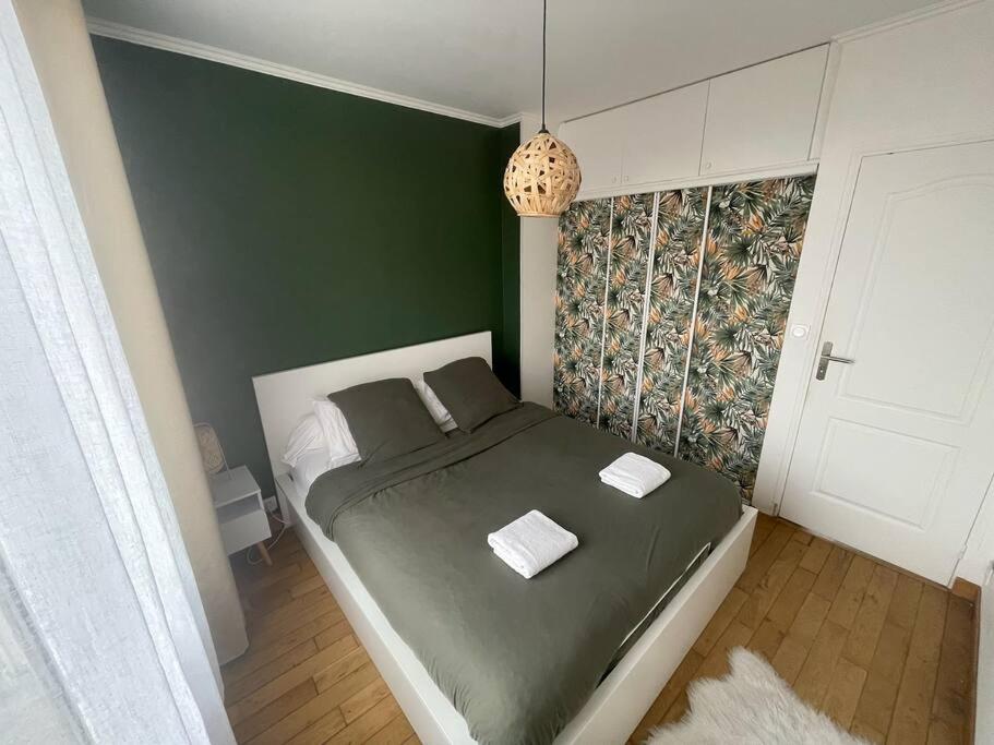 - une chambre avec un lit et un mur vert dans l'établissement Appartement chaleureux proche Paris JO 2024, à Saint-Gratien