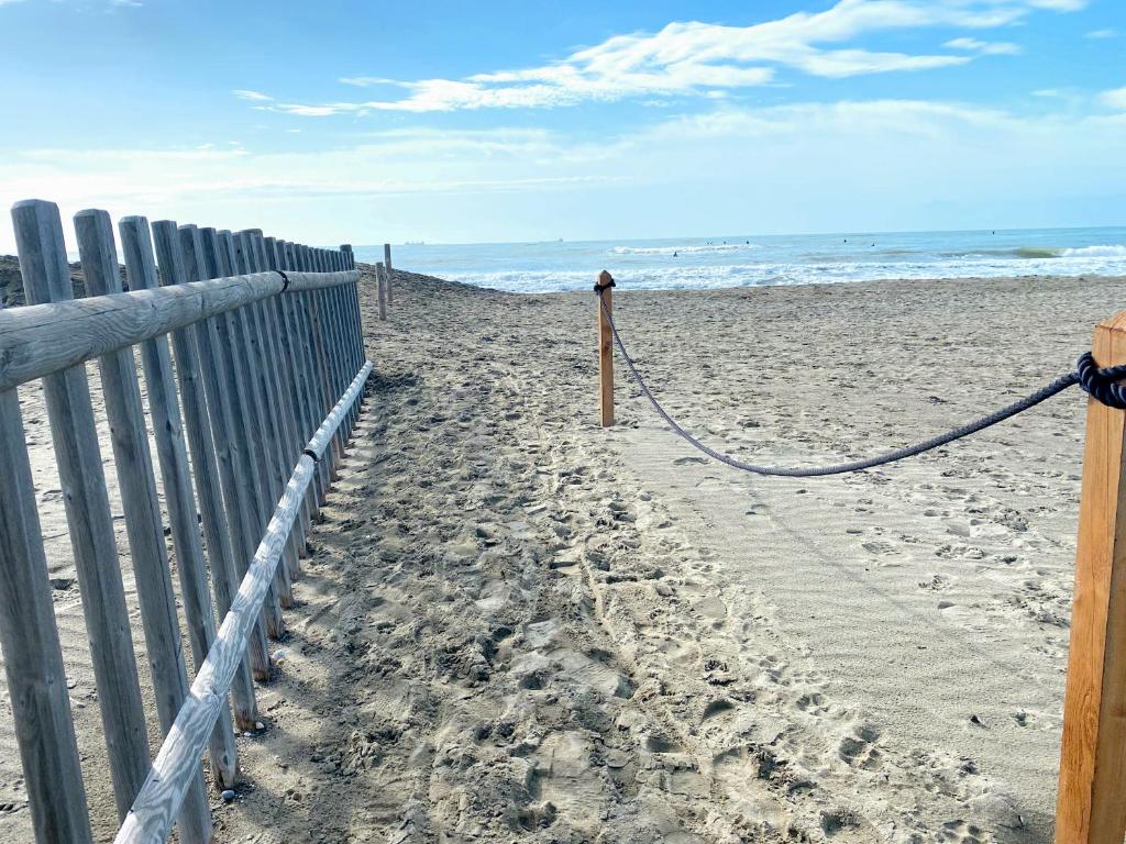 a sandy beach with a fence and the ocean at La Perla di Luni Mare Casa Vacanze in Fiumaretta di Ameglia