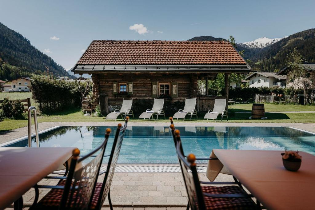 a pool with chairs and a house with a building at BERGZEIT by seven in Flachau