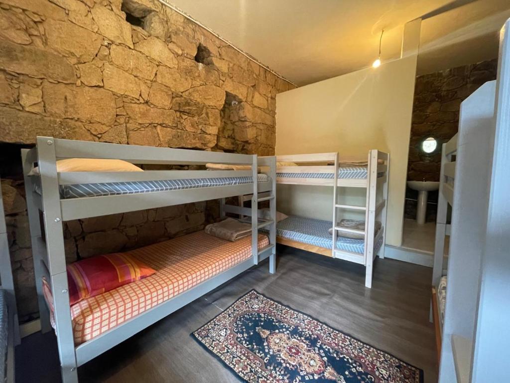 2 Etagenbetten in einem Zimmer mit einer Steinmauer in der Unterkunft Au village in Serriera