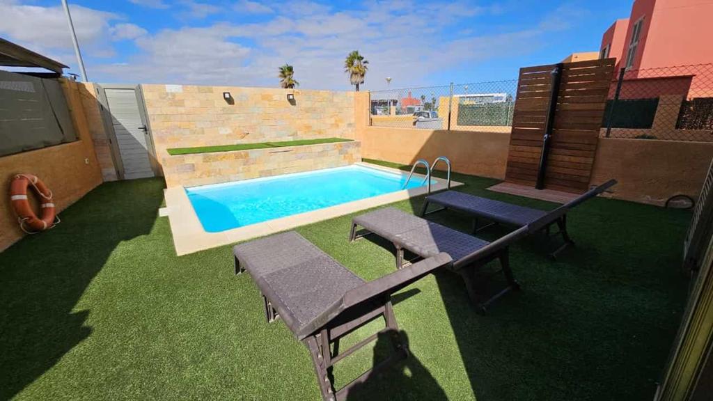 einen Hinterhof mit einem Pool, einem Tisch und Bänken in der Unterkunft El Castillo Golf Salinas-wifi in La Guirra
