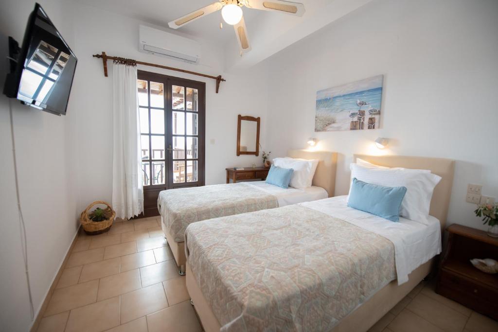 una camera d'albergo con due letti e una televisione di Lilian Beach Front 3 Skopelos a Panormos Skopelos