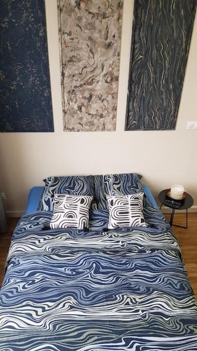 ein Bett mit blau-weißen Laken und Kissen in der Unterkunft Petit studio Magellan in Nantes