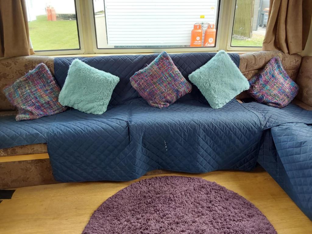 a blue couch with pillows on it in a living room at Sunrise Caravan in Dymchurch