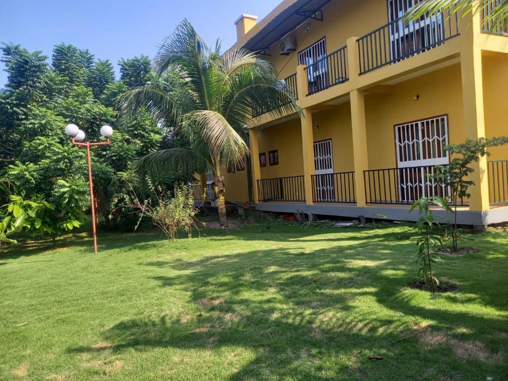 a yellow building with a palm tree in the yard at Moradia Turística MJ ROOMS CITY in São Tomé
