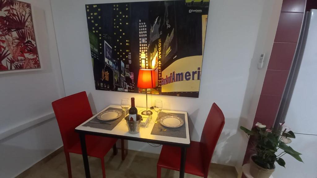 a table with a bottle of wine and two chairs at El estudio de las mariposas,sofa cama , cocina y baño in Partida de La Cañada