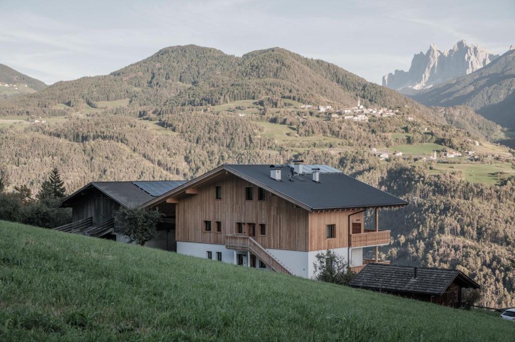 a house on a hill with mountains in the background at Oberhemberger Hof in Feldthurns