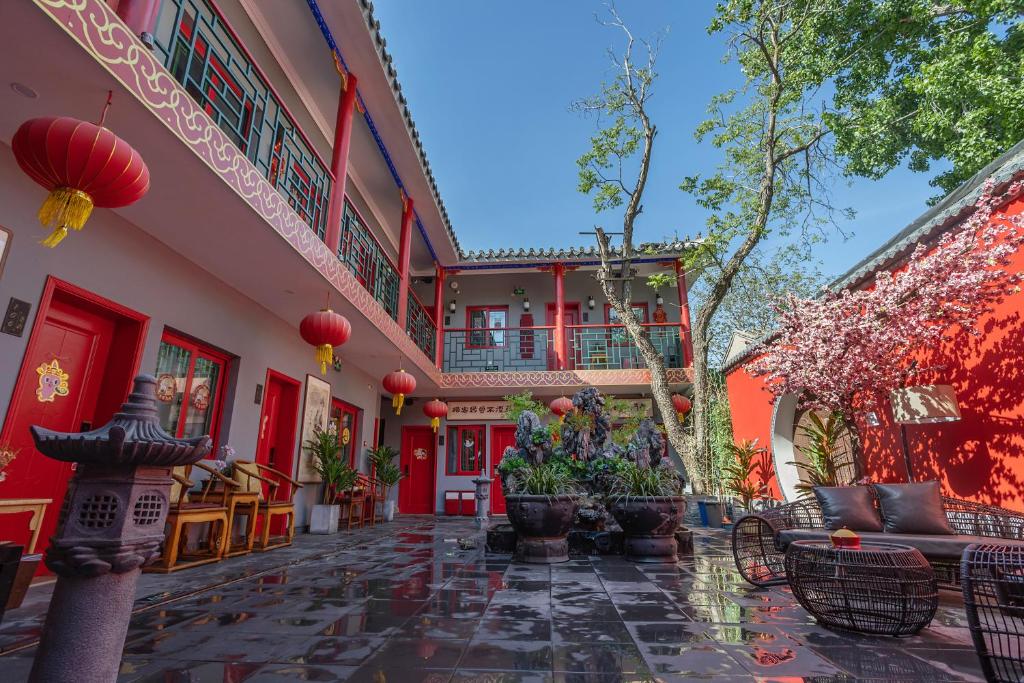 Rong Hotel - Beijing Nanluoguxiang Branch في بكين: ساحة مبنى بجدران حمراء وكراسي