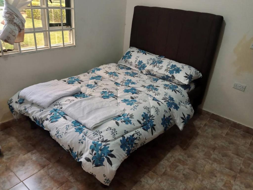 a bed with a blue and white comforter and a window at Kitale Heavenly Haven in Kitale