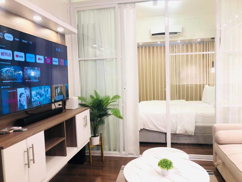 a living room with a tv and a bedroom at Urbanview Oasis at Air Residences in Manila