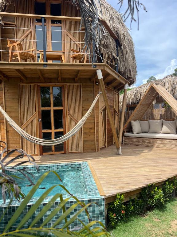 a resort with a thatched building with a pool at JERUSALEMA BEACH GLAMPING in Tolú