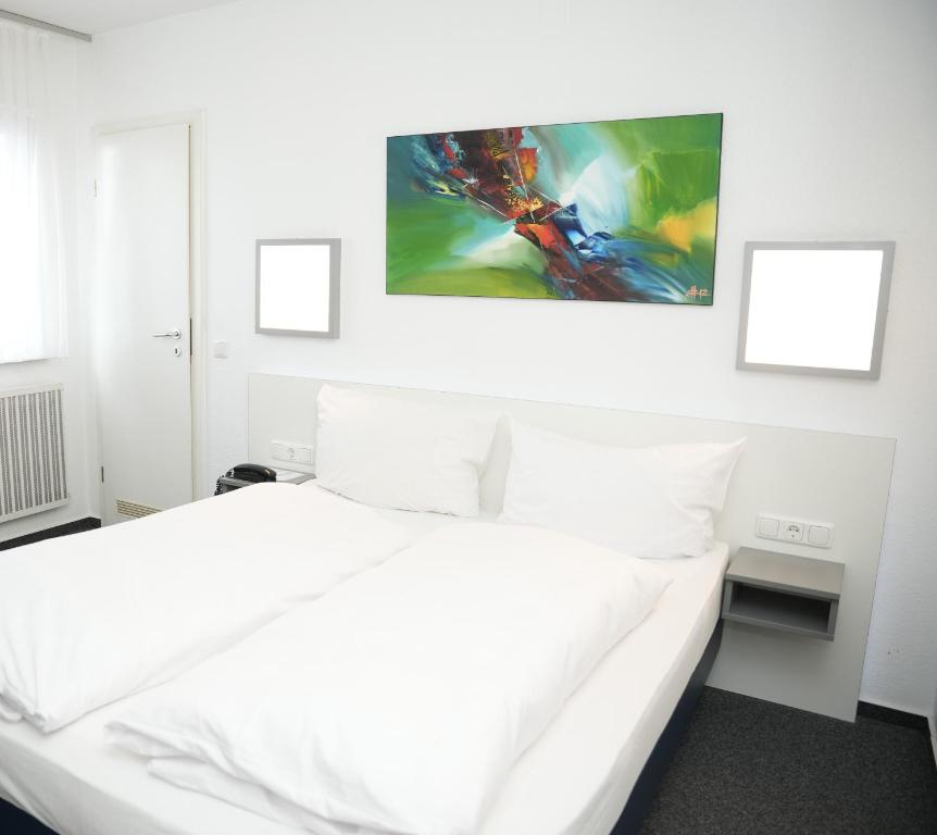 een slaapkamer met een wit bed en een schilderij aan de muur bij Weber Residenz in Mannheim