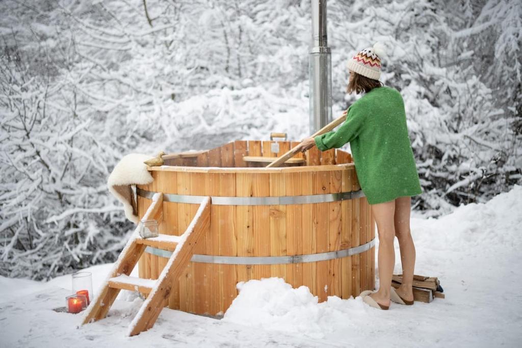 a woman standing in a wooden tub in the snow at Domek Gabi z balią w ogrodzie in Zakopane