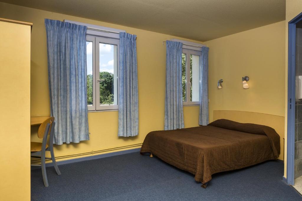 a bedroom with a bed and two windows at Hôtel & Résidence Avermes in Avermes