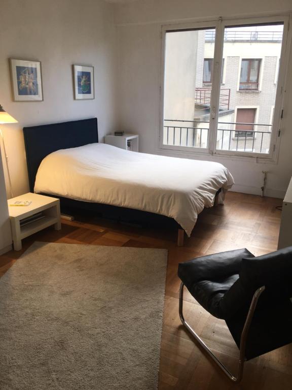 une chambre avec un grand lit et une grande fenêtre dans l'établissement 2 pièces proche tour Eiffel, Trocadéro et OCDE, à Paris