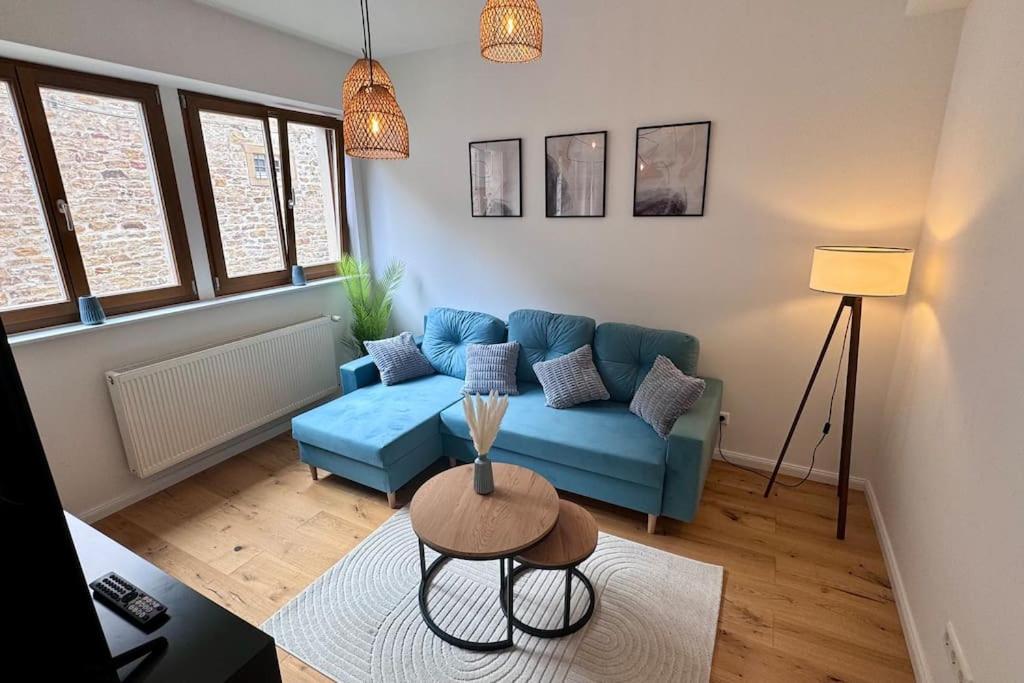 ein Wohnzimmer mit einem blauen Sofa und einem Tisch in der Unterkunft Design Apartment im alten Schloss Deidesheim in Deidesheim