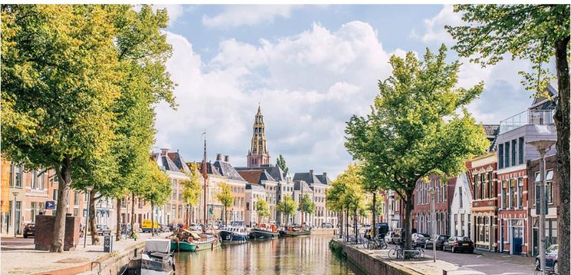 uma cidade com um canal e edifícios e barcos em Het Eiland em Delfzijl