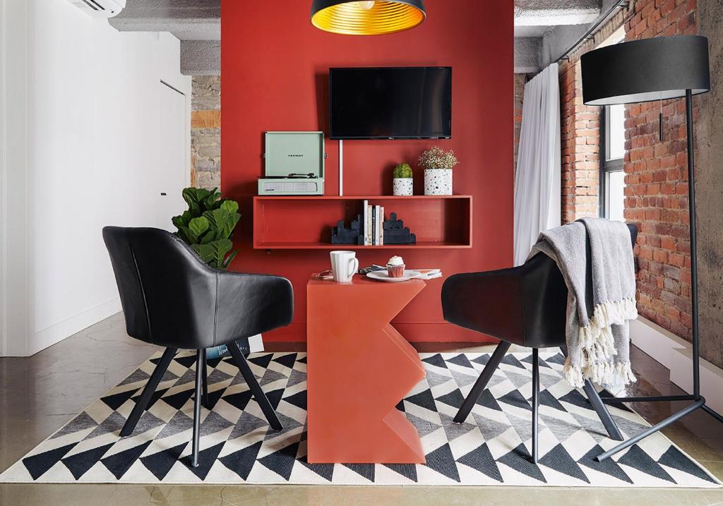 a red wall with two chairs and a table at Maison Sainte-Thérèse By Maisons & co in Montréal