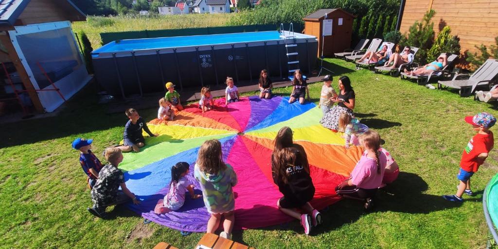 a group of children sitting on a blanket in the grass at Słoneczny Przystanek in Jarosławiec