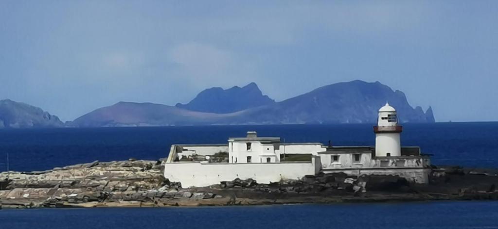 un phare sur une île dans l'eau avec des montagnes dans l'établissement Horizon View Lodge Bed and Breakfast Glanleam Road Knightstown Valentia Island County Kerry V23 W447 Ireland, à Île de Valentia