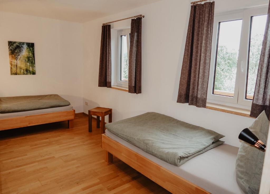 1 dormitorio con 2 camas y 2 ventanas en Ferienwohnung/Arbeiterwohnung Kampenwand en Rohrdorf