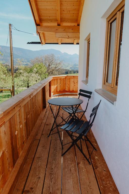 a table and two chairs on a wooden balcony at Ferienwohnung/Arbeiterwohnung Kampenwand in Rohrdorf