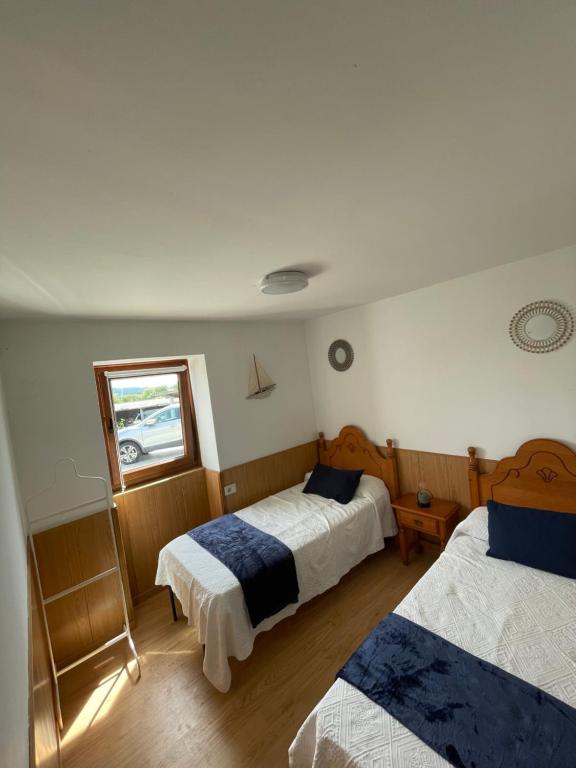 1 dormitorio con 2 camas y ventana en CASA DA TORRE, en O Grove