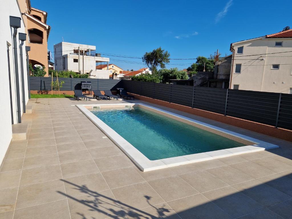 a swimming pool on the side of a house at Apartmani Relaxsea in Privlaka