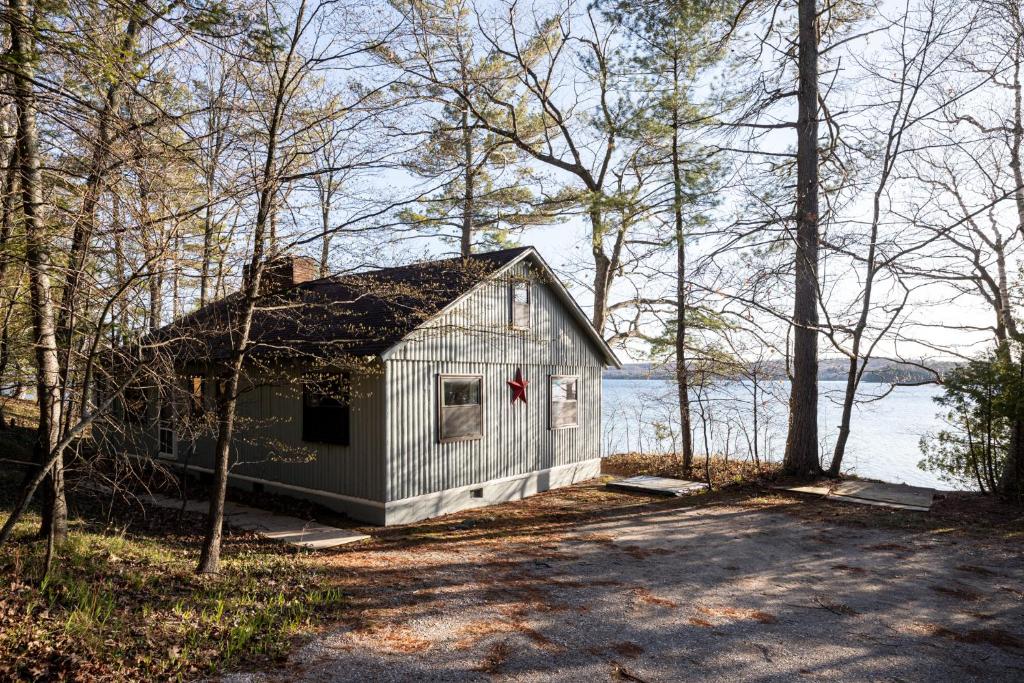 a small white house in the woods with a lake at Omena Point Paradise Waterfront Sunrise in Suttons Bay