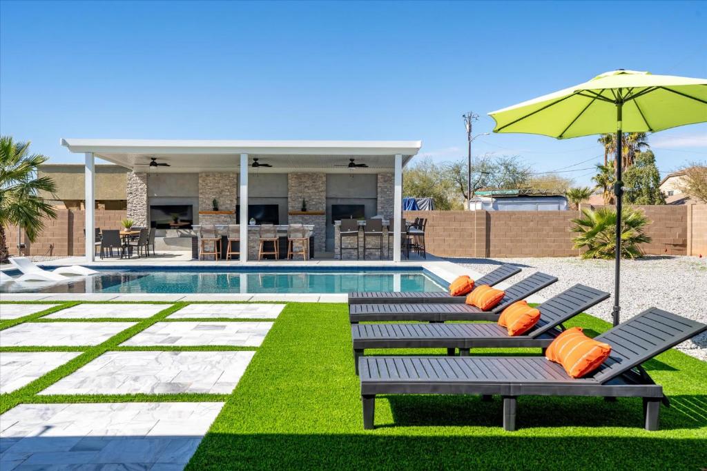 una piscina con dos bancos y una sombrilla en Backyard Oasis Heated Pool Game Room Gazebo en Phoenix