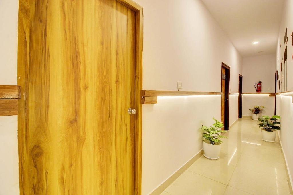 a hallway with a wooden door and potted plants at Casa Grand Hotels Nacharam in Hyderabad