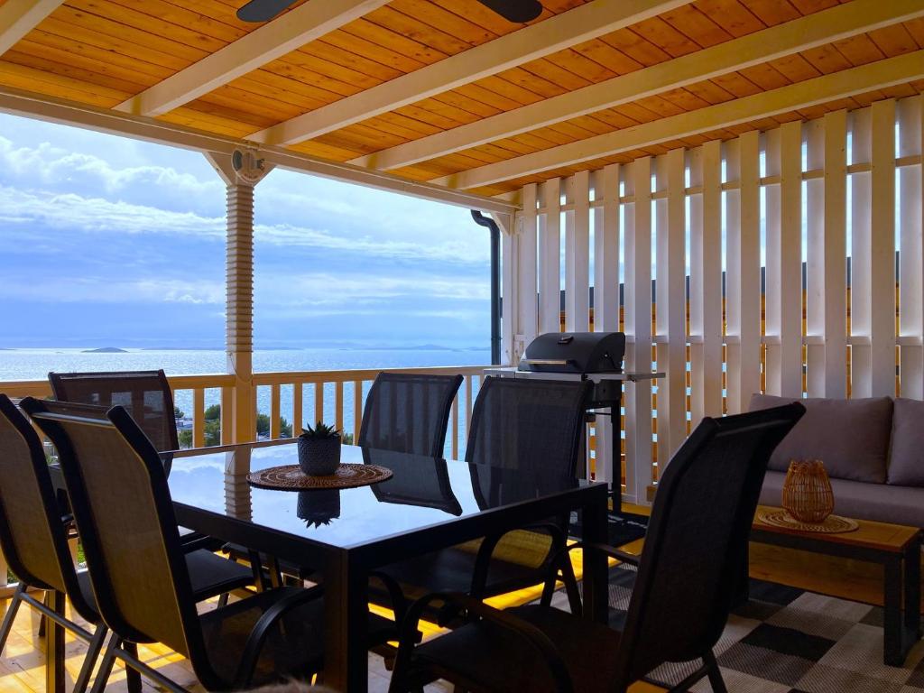 a screened in porch with a table and chairs at Mobile Home SkyLine - beautiful sea view - on the palm of the beach in Drage