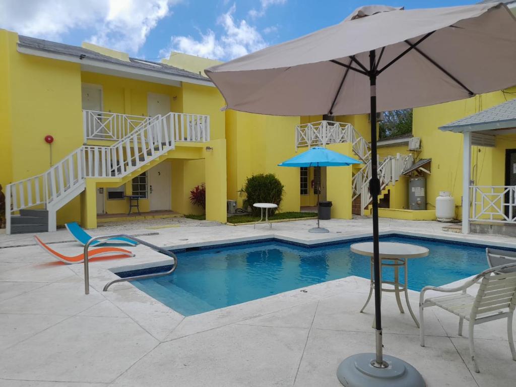 einem Pool mit Stühlen und einem Sonnenschirm neben einem Gebäude in der Unterkunft Sun Fun Hotel in Nassau