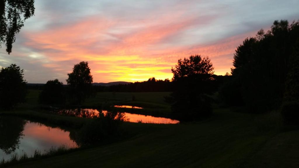 a sunset over a pond in a field at Auszeit am Land in Kemnath